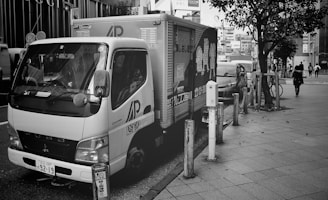 A delivery vehicle parked in front of a cityscape.