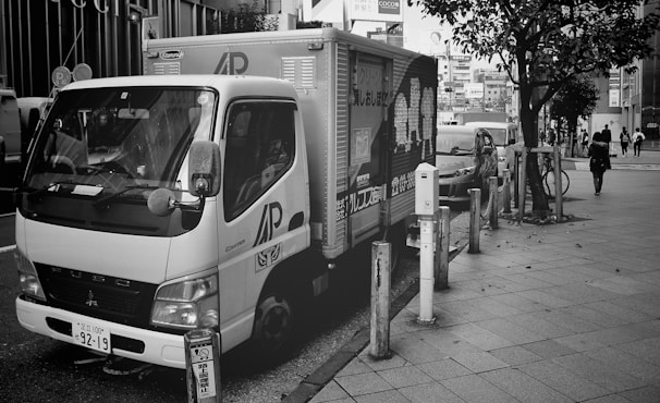 A delivery vehicle parked in front of a cityscape.