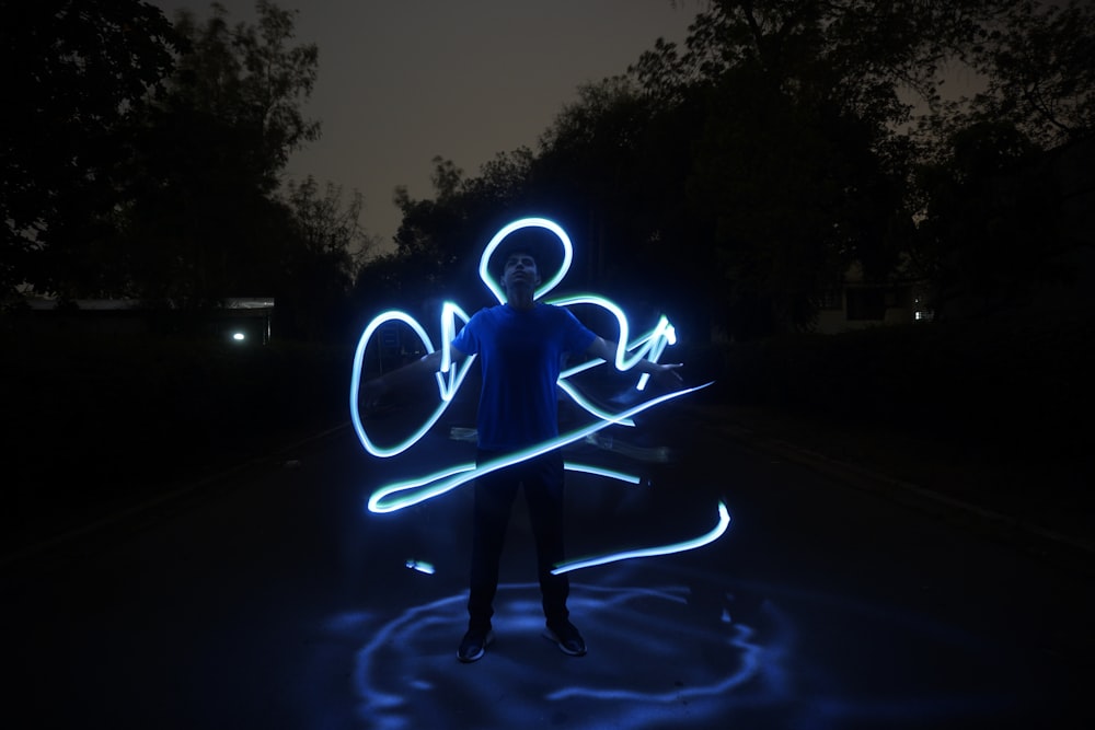 a man standing in the middle of a road holding a light painting