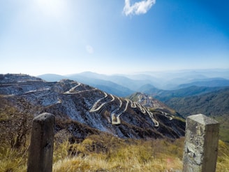 aerial photography of green field viewing mountain under blue and white sky during daytime