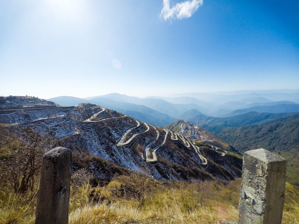 aerial photography of green field viewing mountain under blue and white sky during daytime