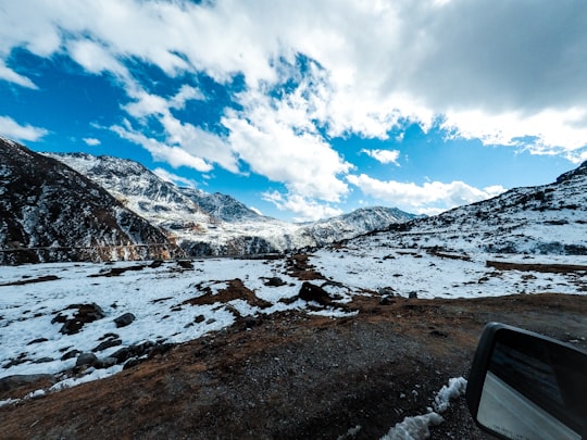 field and mountain covered with snow under white and blue sky during daytime in Sikkim India