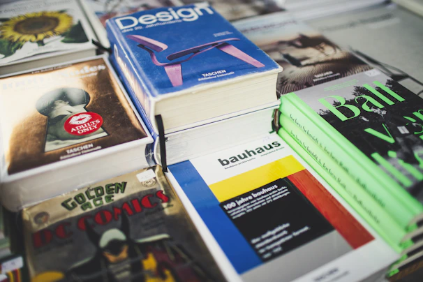 Stack of graphic books with bold, artistic covers displayed on a wooden table