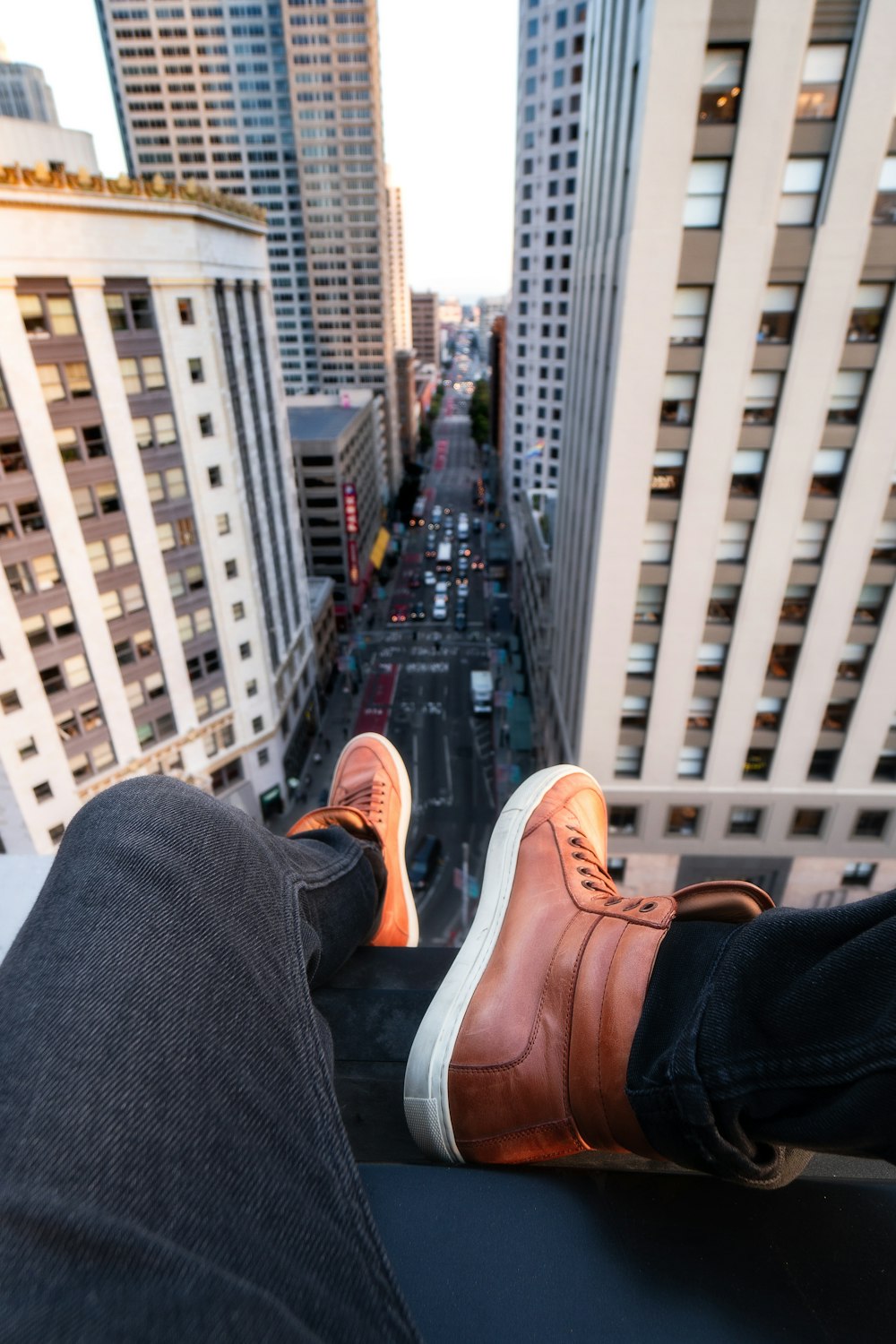 Person in black jeans and brown high-top sneakers sitting on rooftop with  view of streets between buildings photo – Free San francisco Image on  Unsplash