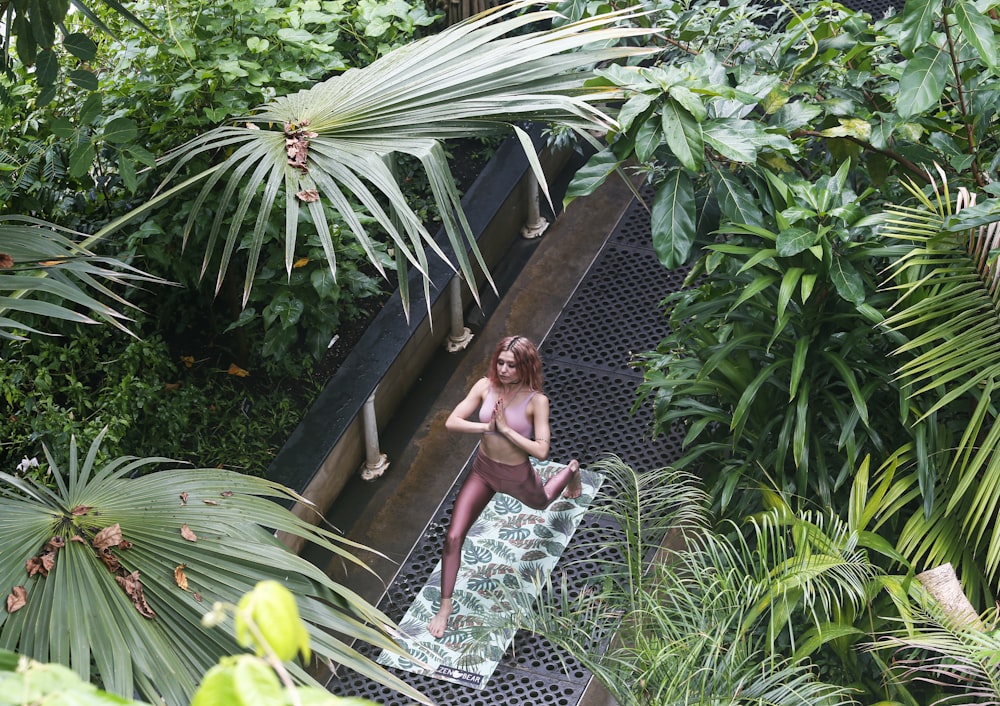 woman doing yoga exercise near trees during daytime