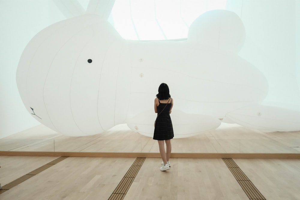 woman in black minidress standing near white animal float