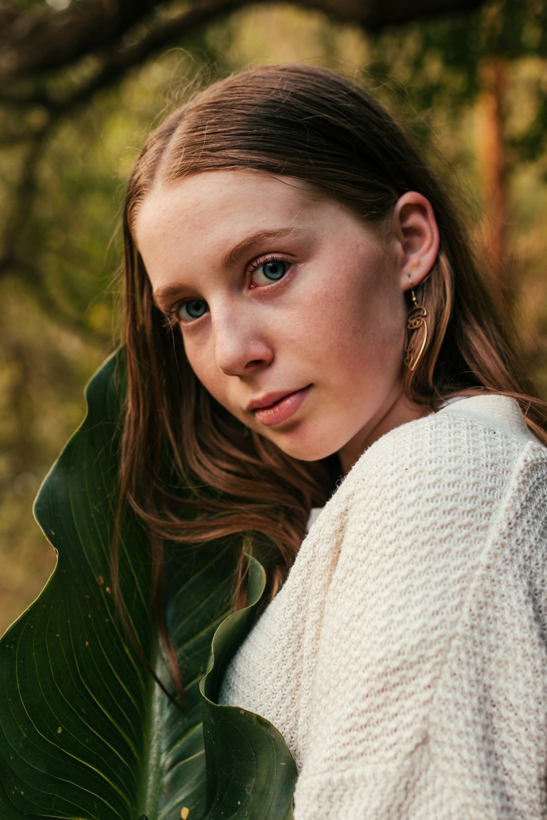 woman wearing white crew-neck sweater standing near green leaf plant glancing her right side