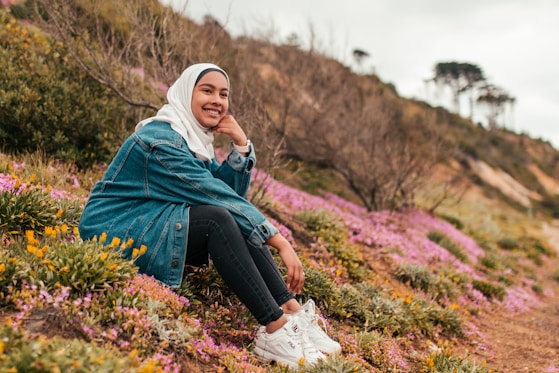 woman sitting on hill wearing gray denim jacket and white hijab scarf