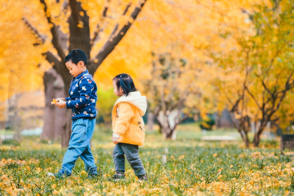 girl and boy walking beside tree