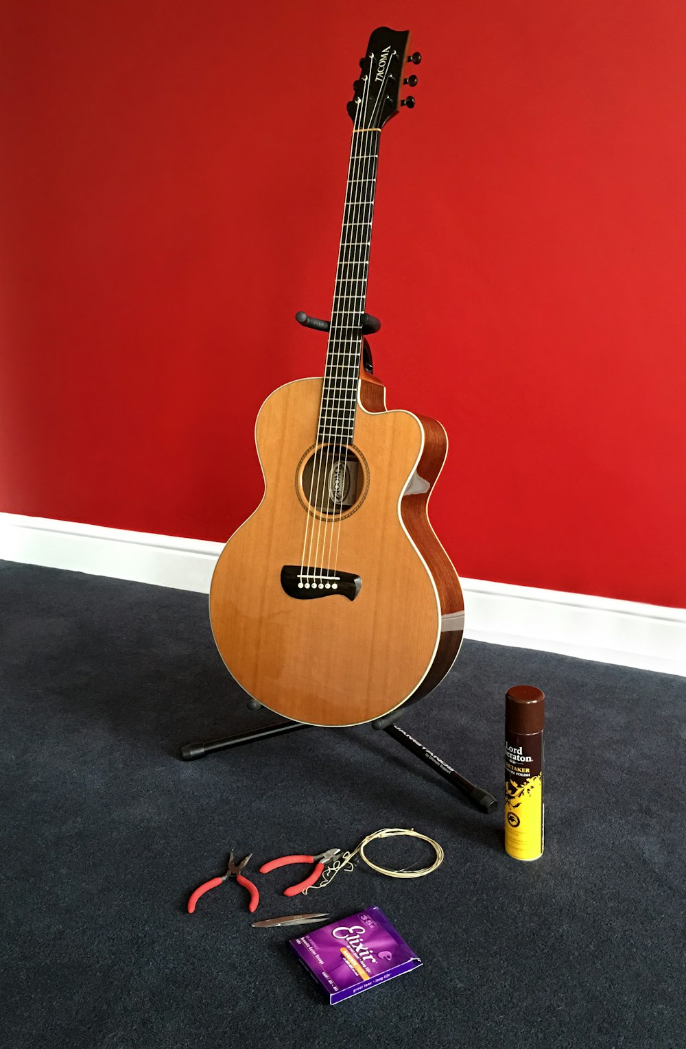 brown acoustic guitar near red handled pliers and spray can