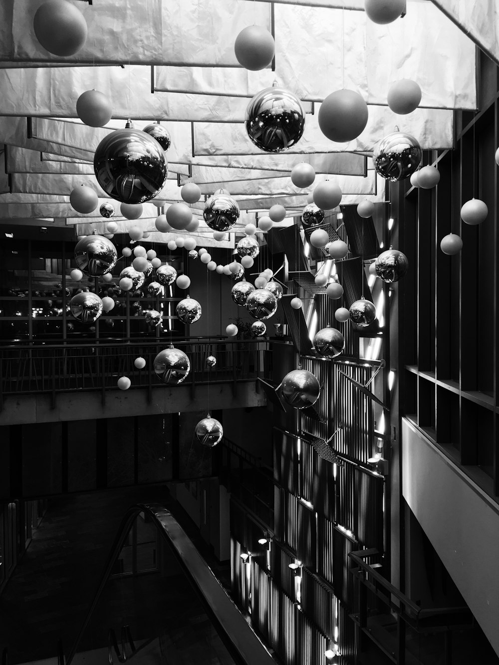 a black and white photo of a building with lots of balloons hanging from the ceiling