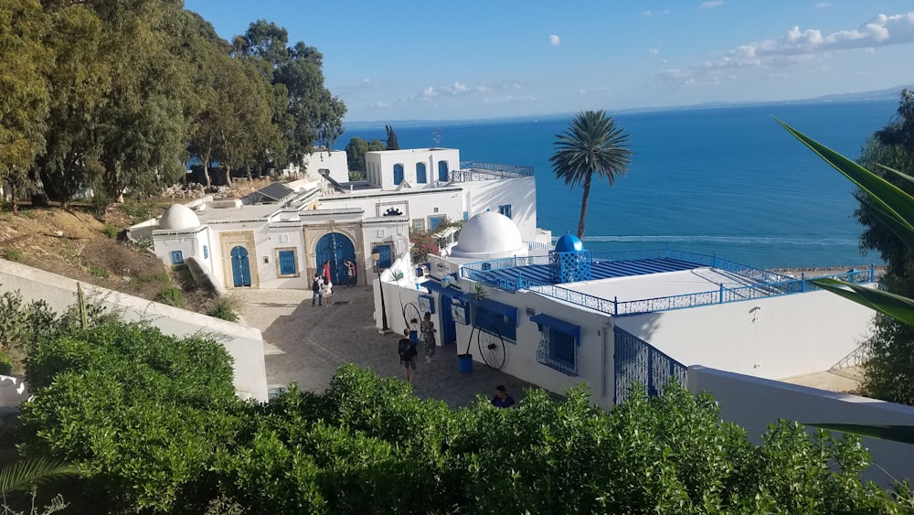 Menschen in der Nähe von White and Blue Seaside Resort betrachten blaues Meer unter blauem und weißem Himmel