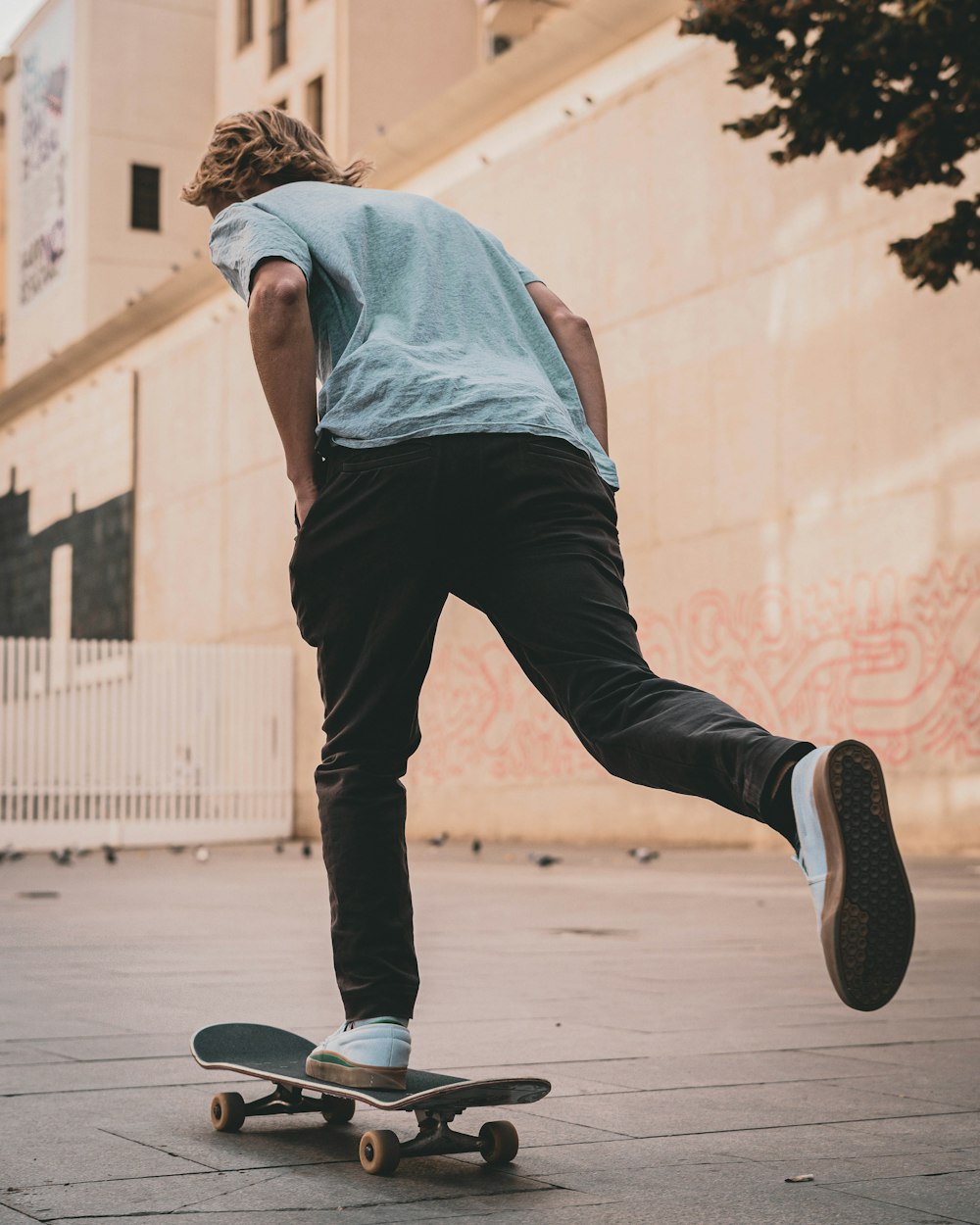 man in grey shirt skating beside building