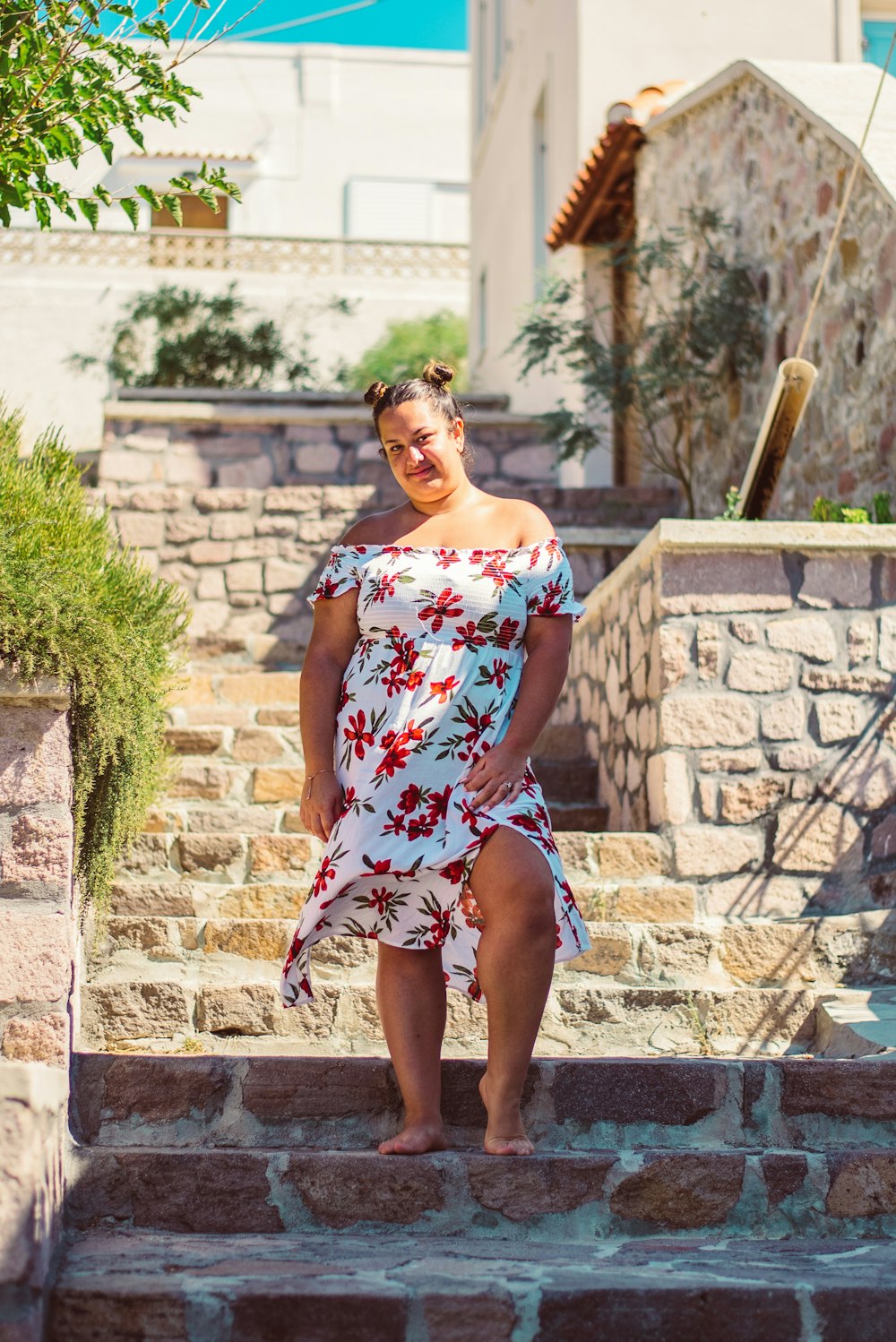 Mujer en vestido de tubo floral blanco y rojo de pie en escaleras de hormigón