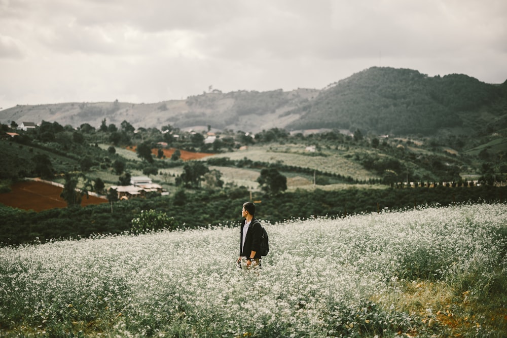 man standing surrounded with white flowers during daytime