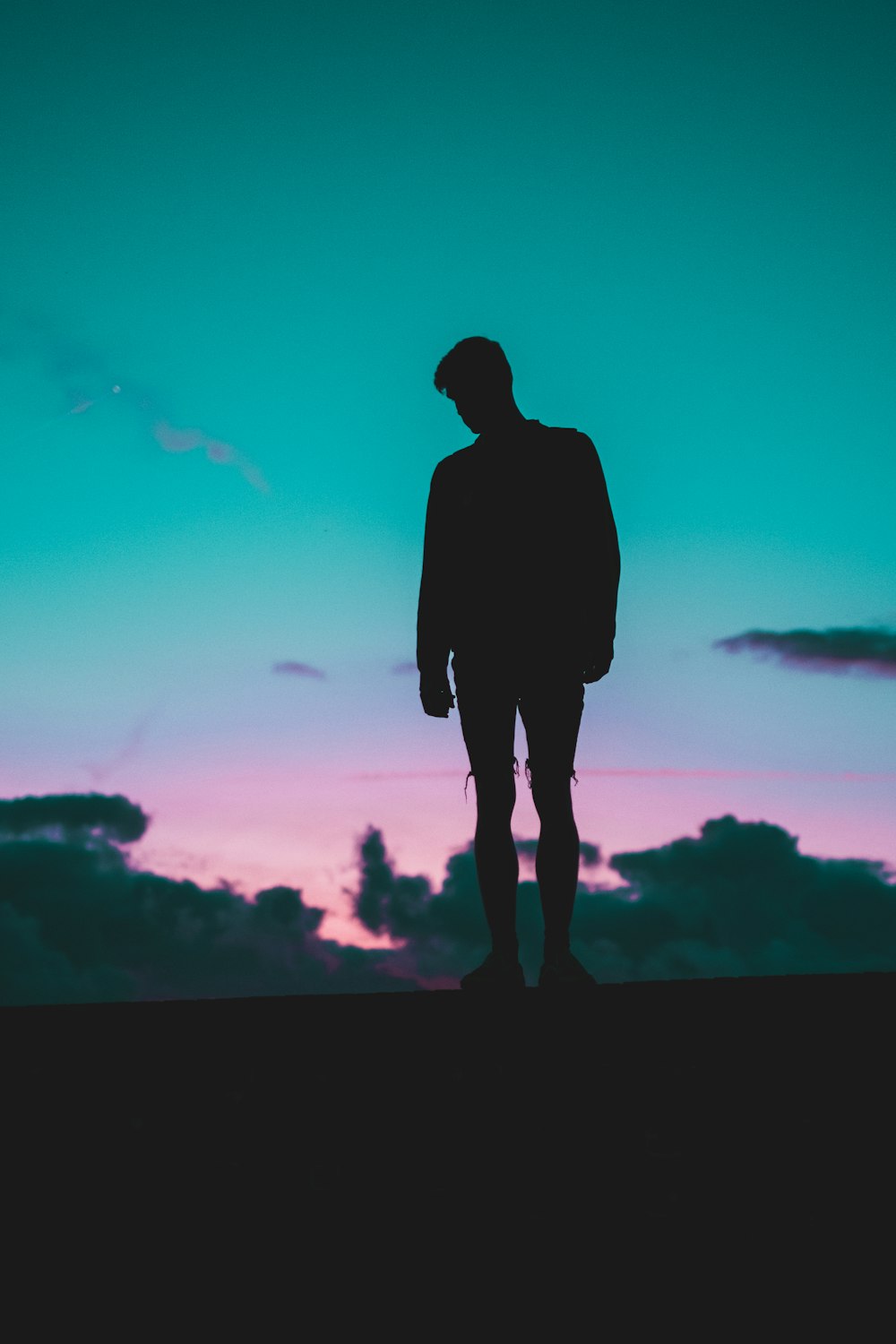 a man standing on top of a hill under a purple and blue sky