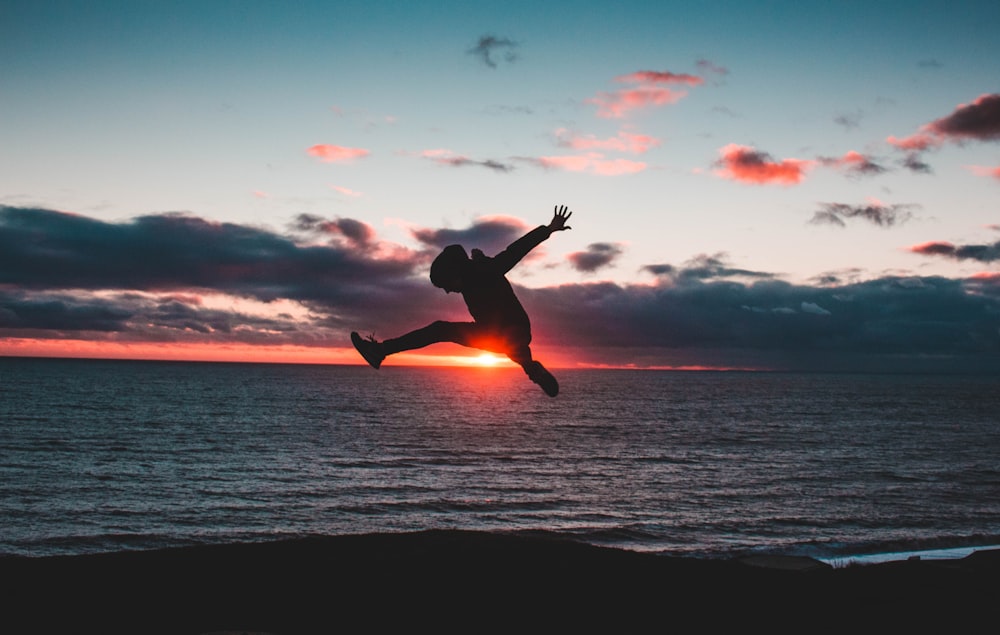 man jumping near the body of water