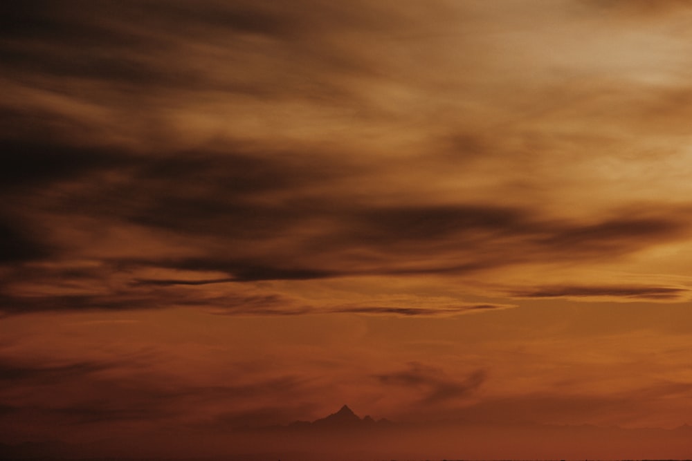 a plane flying through a cloudy sky at sunset