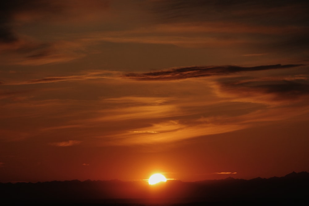 the sun is setting in the sky over the mountains