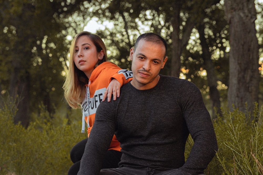 man and woman sitting under trees