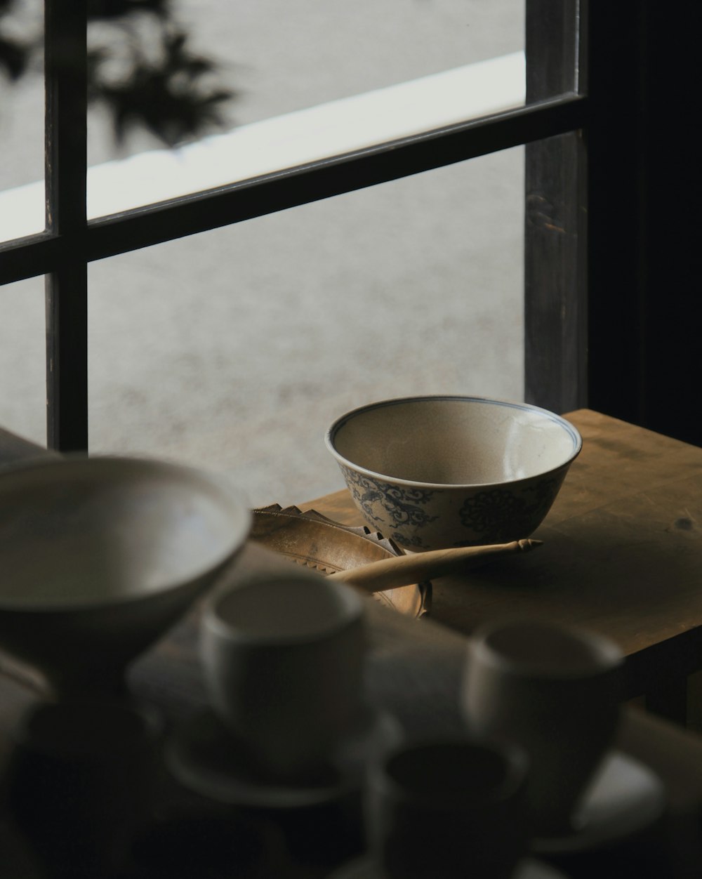 round white and blue ceramic bowl on wooden table near glass window