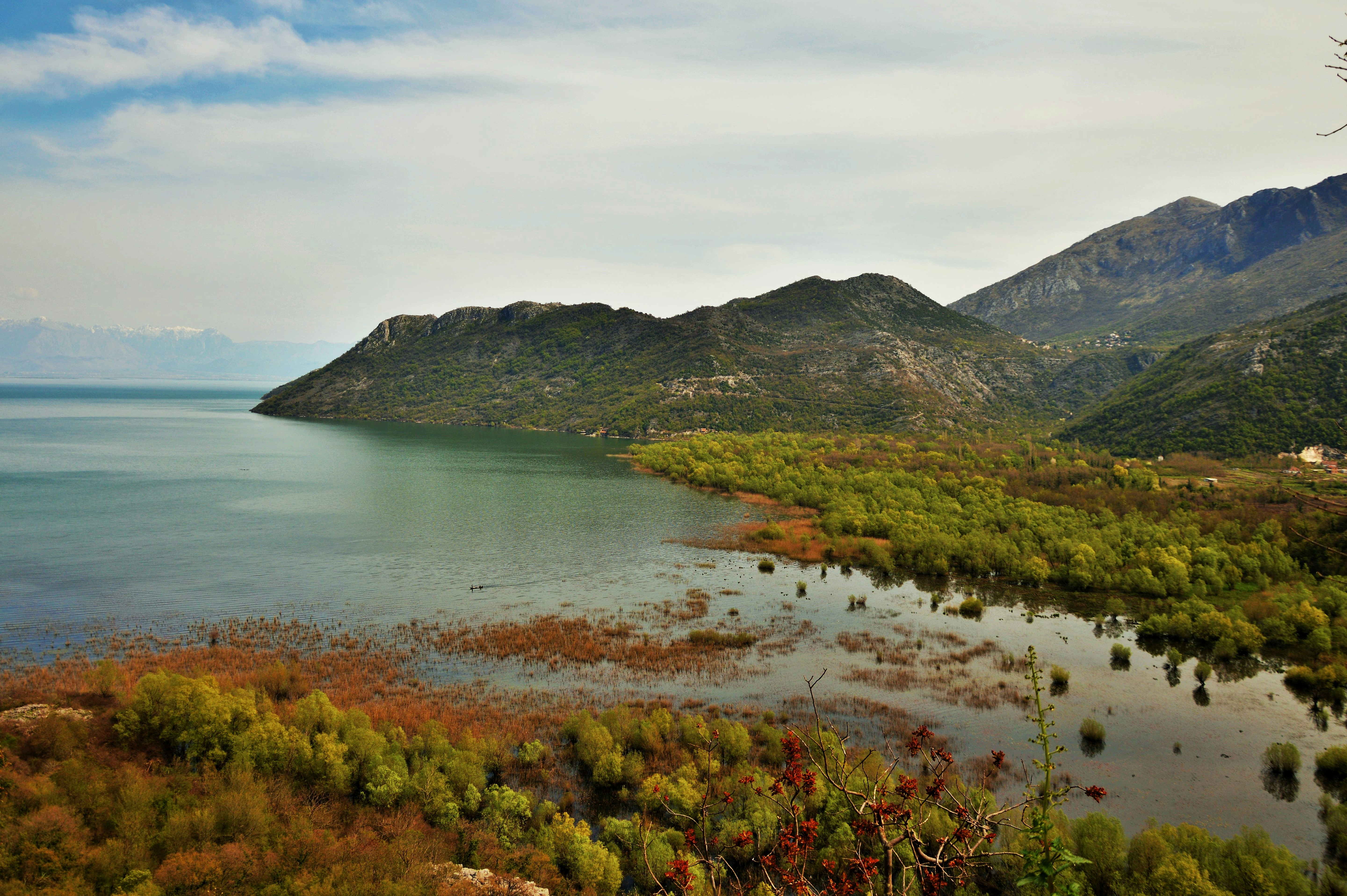 aerial photography of body of water viewing mountain under white and blue sky during daytime
