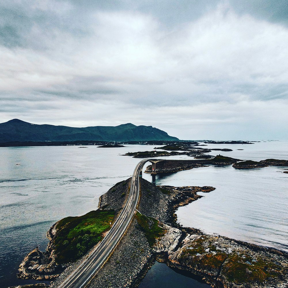 aerial photography of gray road viewing sea and mountain under white sky