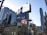 A bustling urban scene with tall buildings and numerous advertisements including prominent brands like Bell and McDonald's. The architecture features a mix of glass and steel structures, with large digital billboards displaying various products and services. There are traffic lights and street signs visible, contributing to the city's busy ambience.