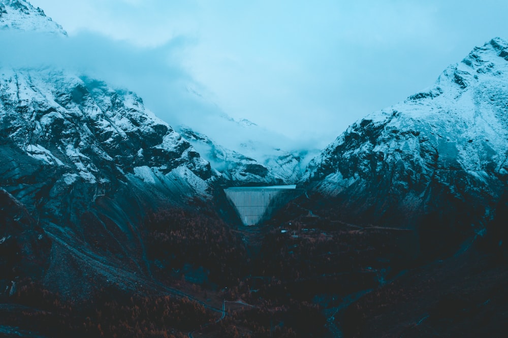 a mountain covered in snow with a bridge in the foreground