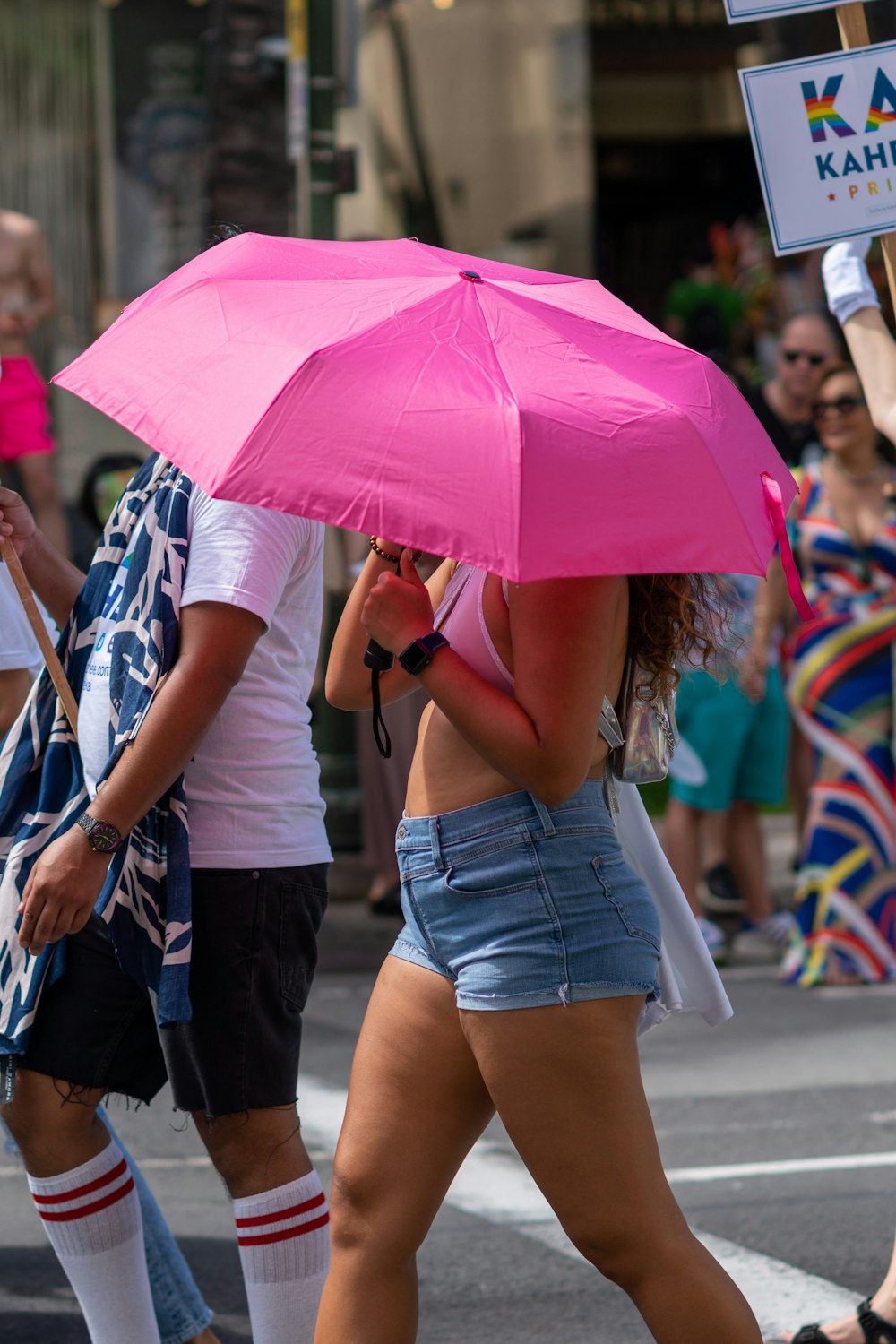 분홍색 우산을 쓰고 흰 브래지어를 입은 여자가 사람들로 둘러싸인 통로에서 깨어나고 있다.
