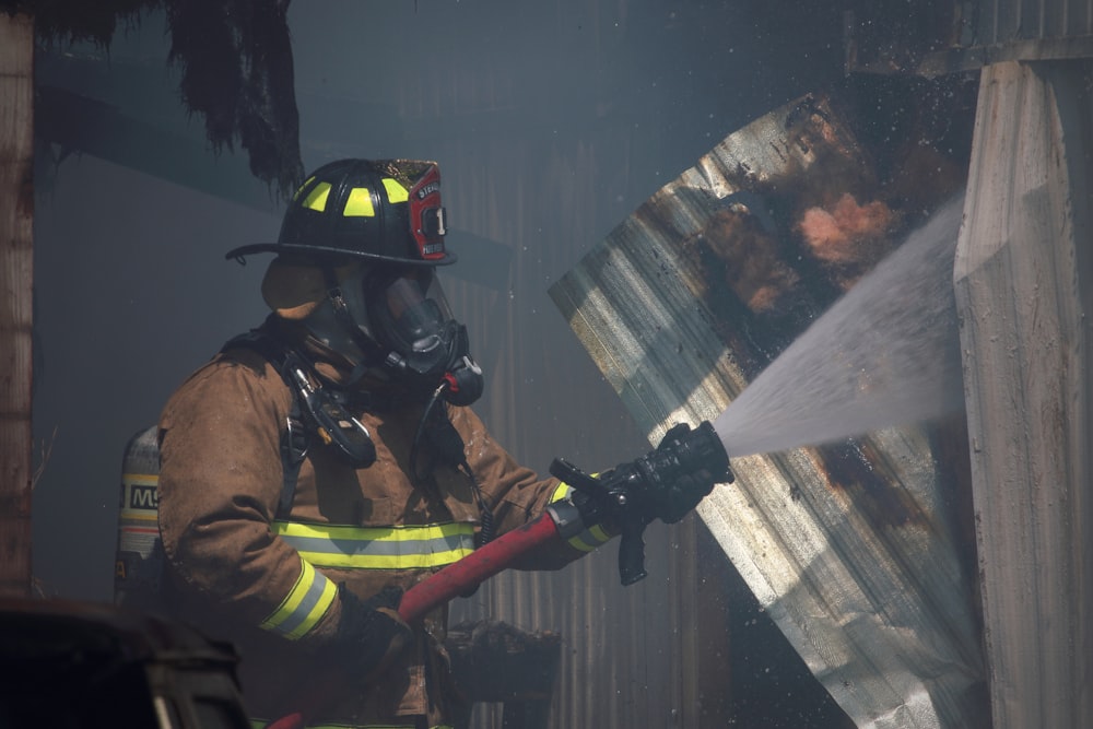 shallow focus photo of firefighter using red water hose