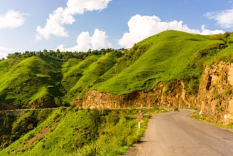 A scenic highway winding through lush green hills under a clear blue sky.
