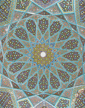 Intricate blue and yellow geometric tile mosaic on a domed ceiling