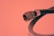 A close-up view of a coaxial cable connector with a metal tip and threaded base. The background is a solid color, adding emphasis to the cable's features and structure.