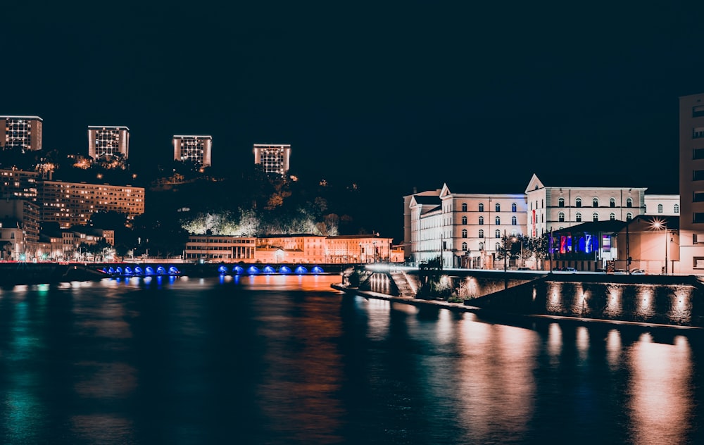 city with high-rise buildings viewing body of water during night time