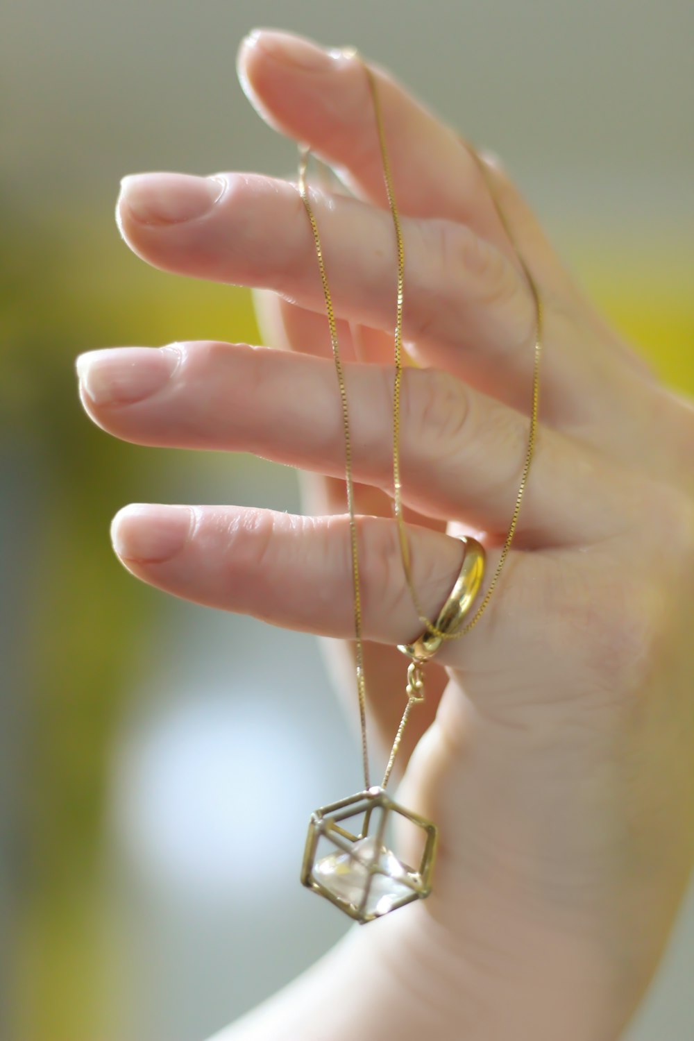 shallow focus photo of person holding gold-colored necklace with pendant