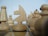 Several wooden chess pieces are arranged on a chessboard. The focus is on the knight in the center, surrounded by pawns and rooks. The pieces have a natural wood grain texture and are positioned closely, suggesting a strategic game setup.