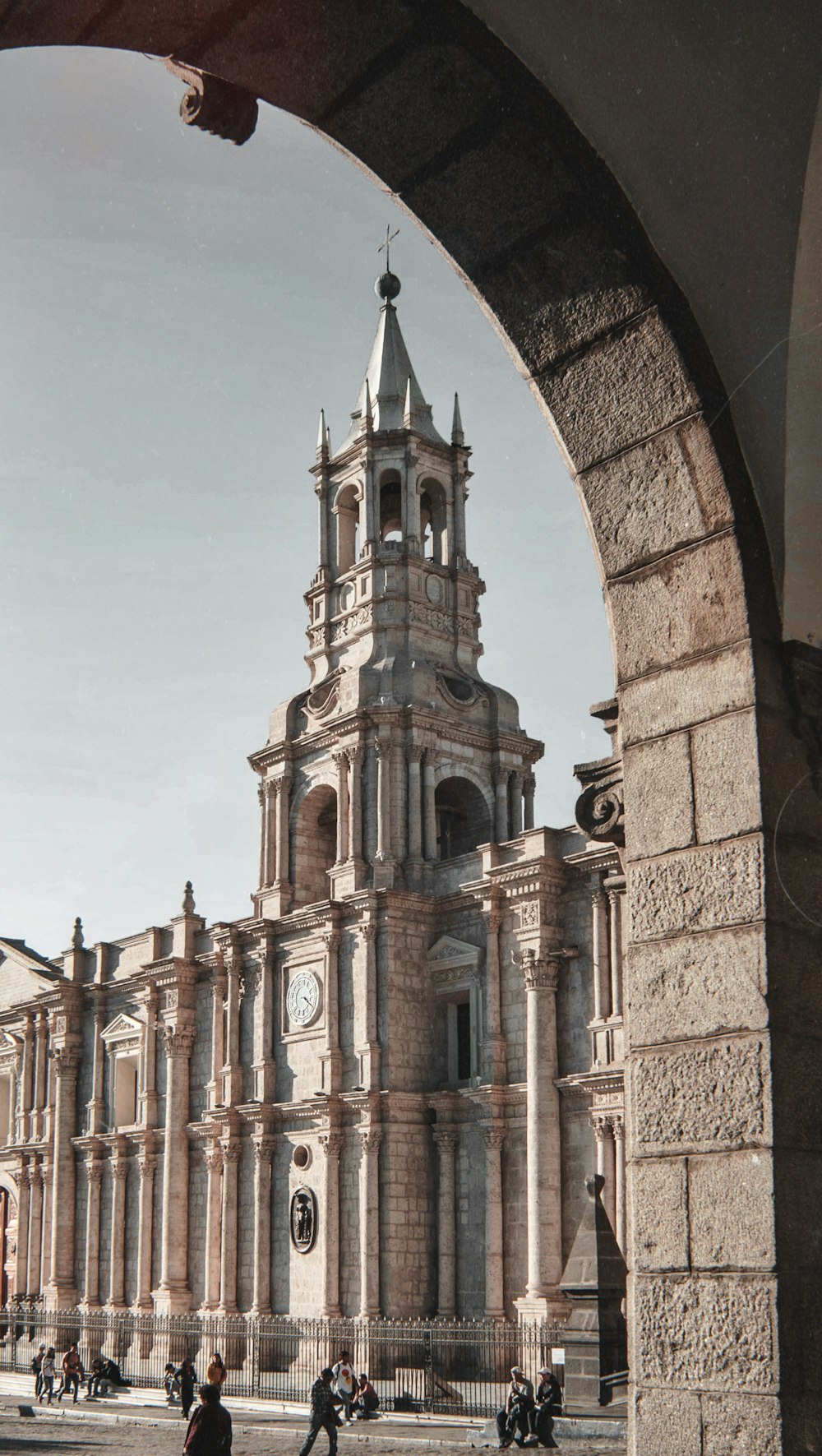 Menschen, die neben der grauen Betonkirche spazieren gehen