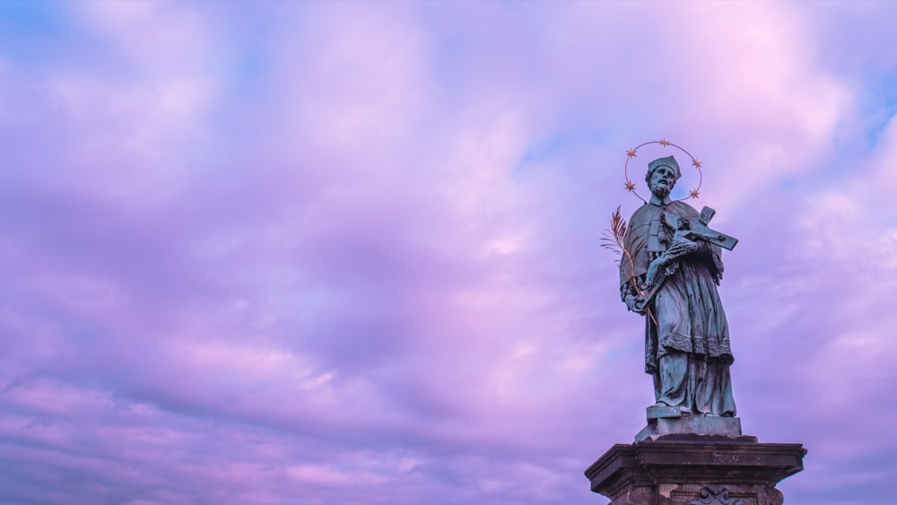 gray man holding cross statue