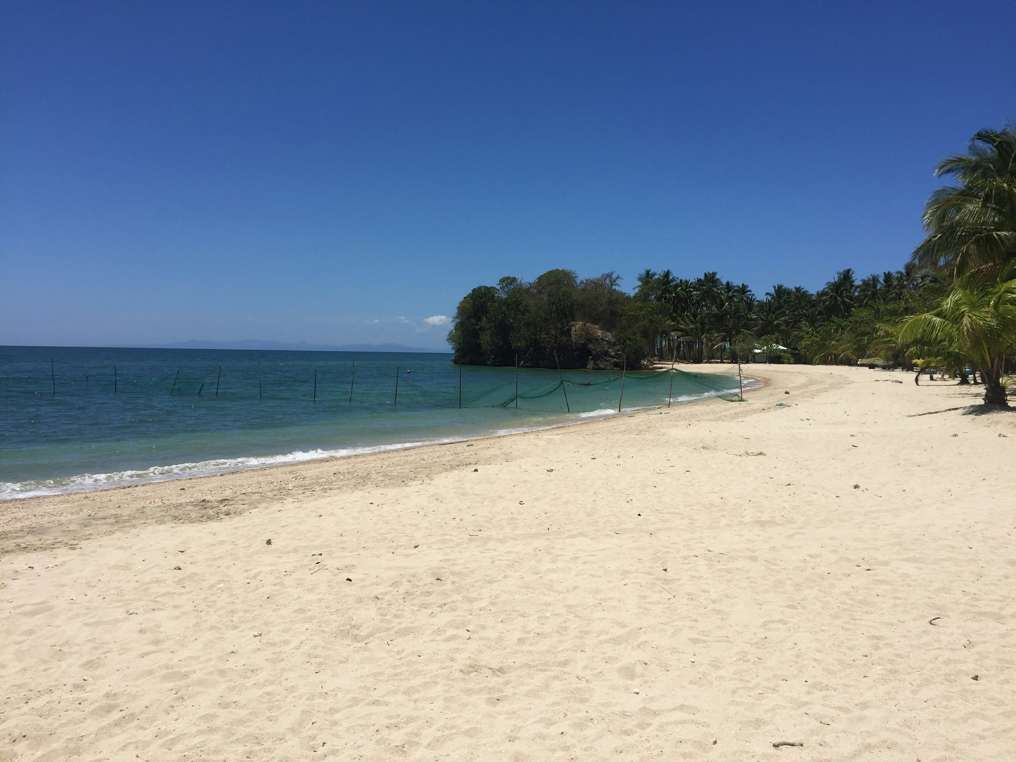 view photography of white sand and blue sea under clear blue sky
