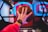 A hand wears a digital watch and holds a basketball, aiming towards a basketball hoop with vibrant neon lights in the background, creating a dynamic and energetic atmosphere.