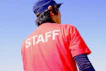 male staff wearing red t-shirt and blue hat standing