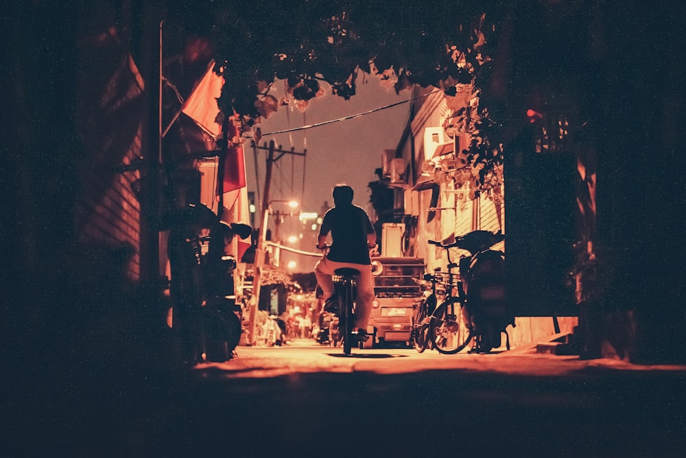 person riding motorcycle near houses during night time