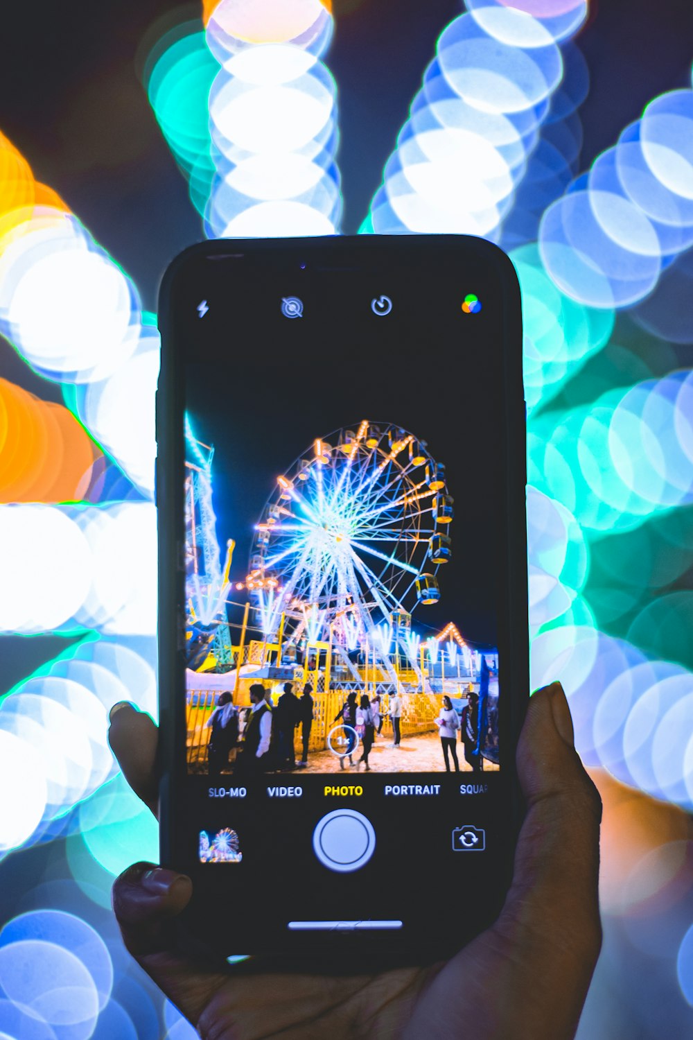 shallow focus photo of person taking photo of Ferris wheel using smartphone