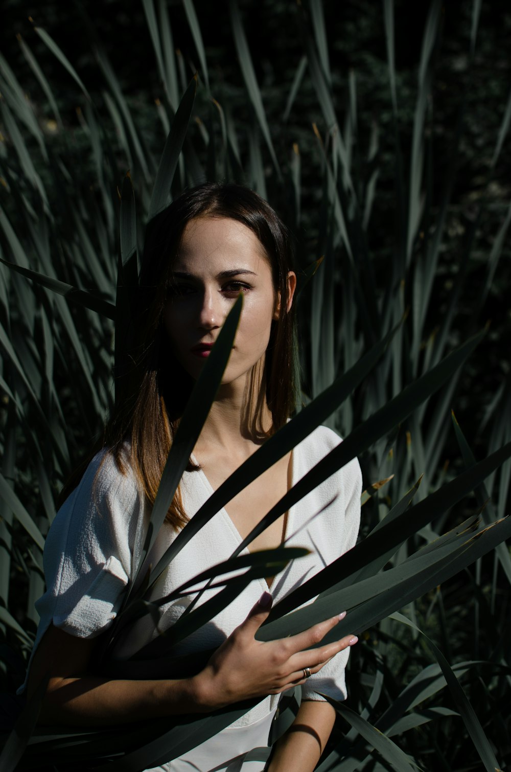 woman in white shirt holding plant