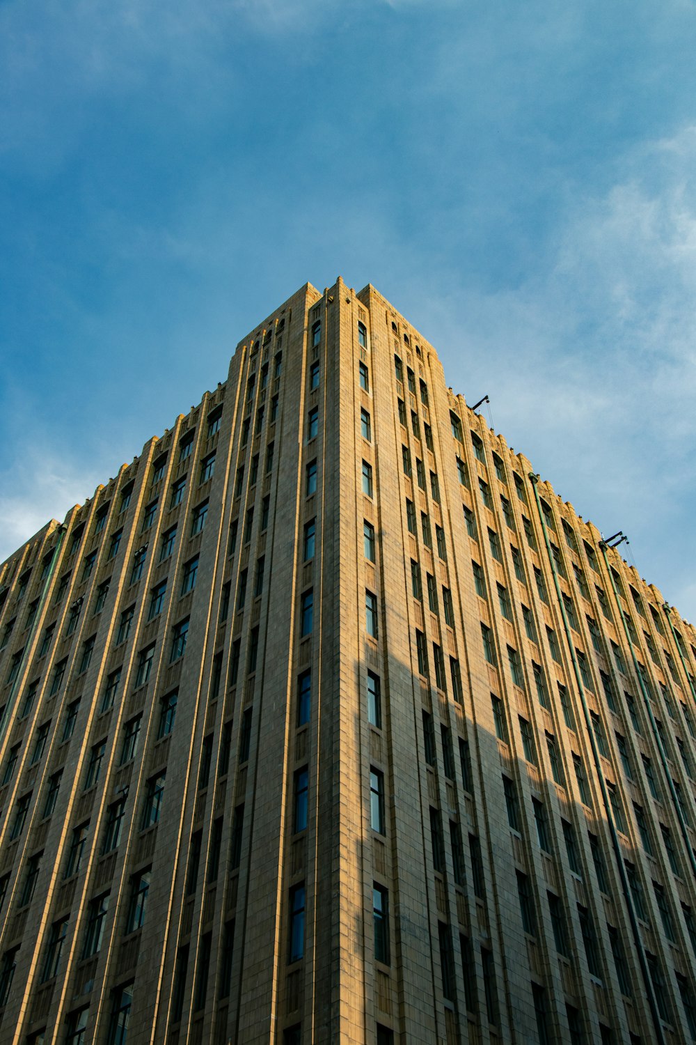 Low-Angle-Fotografie eines braunen Hochhauses unter einem ruhigen blauen Himmel