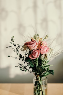 A delicate arrangement of soft pink and white roses in a sleek glass vase.