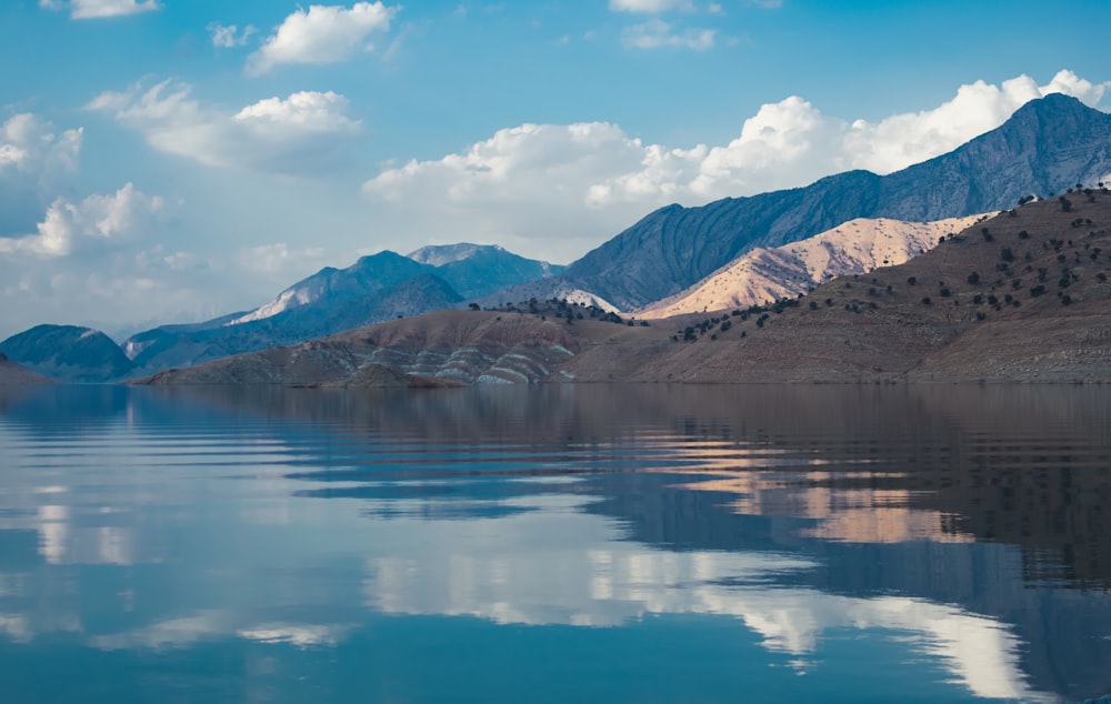 body of water near snow-covered mountain during daytime