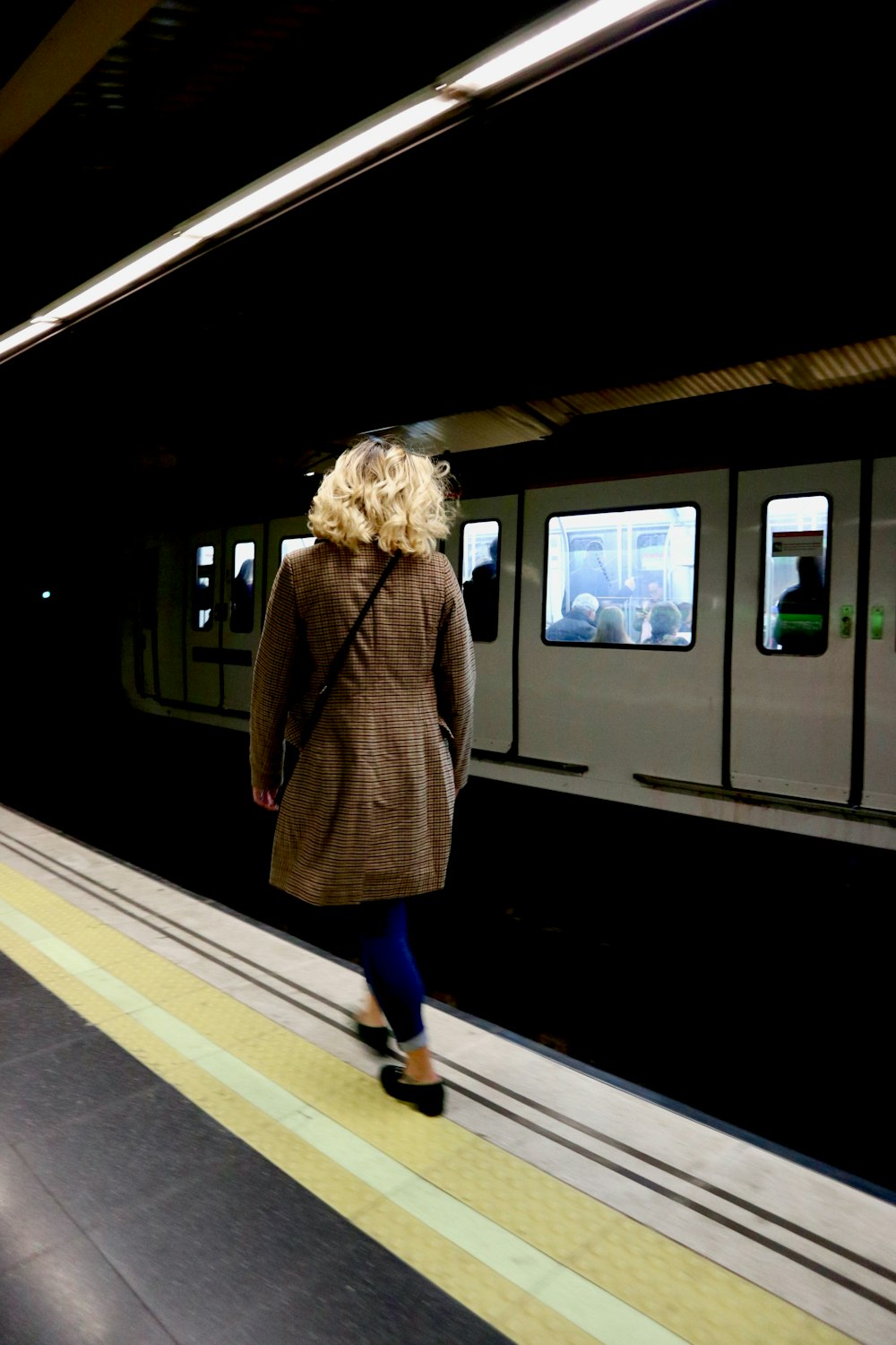 woman wearing brown coat standing near train