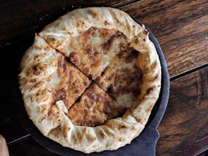 Close-up of a freshly baked pizza with melted cheese and colorful toppings on a rustic wooden table.